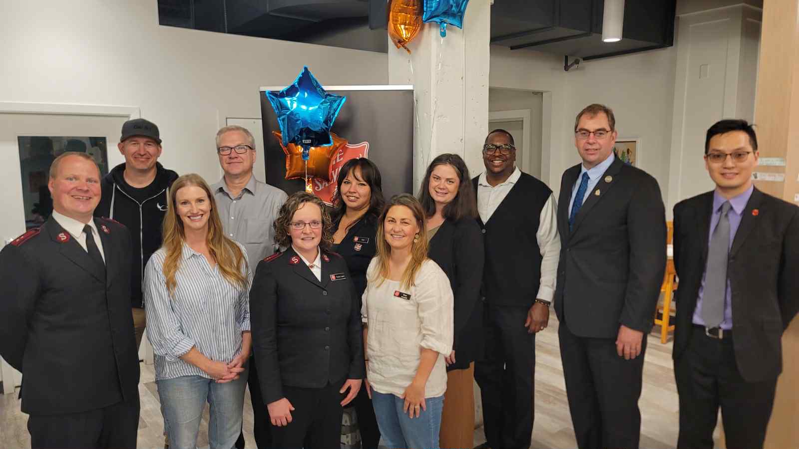 Team members of the Salvation Army Connection Point Church and Resource Centre standing together indoors in a community space, posing for a group photo with star-shaped balloons and interior fixtures visible in the background.