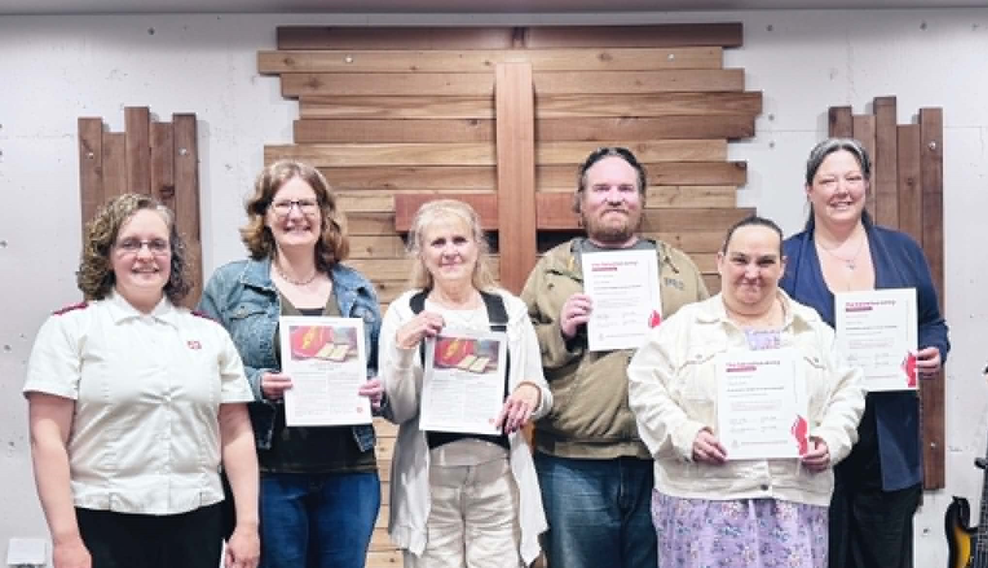 Captain Laura (Corps Officer), stands with newest members of the church who are holding their certificates. 